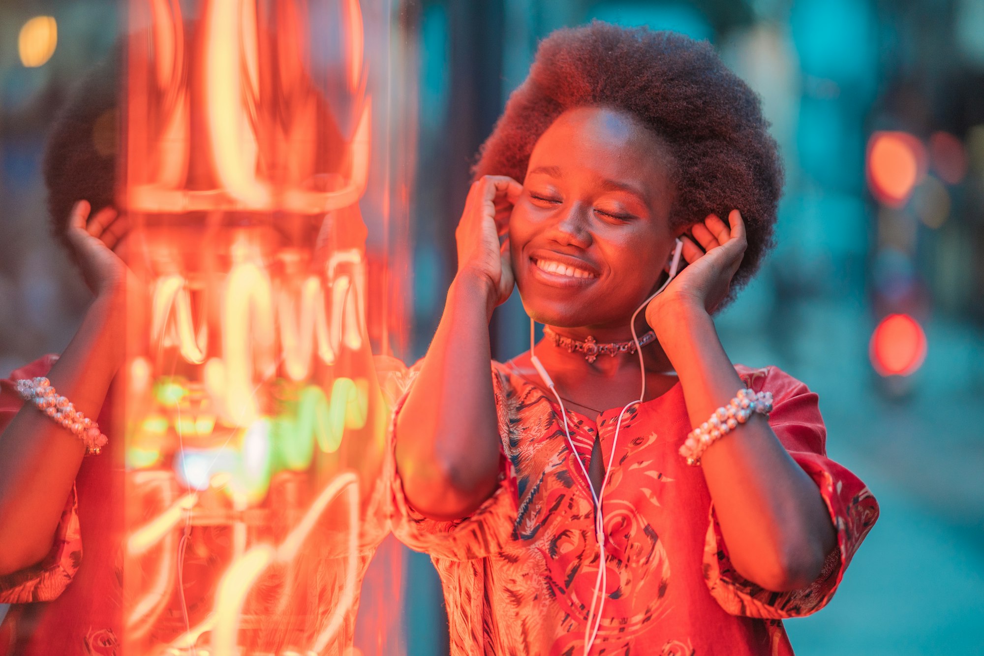 Smiling young woman with headphones standing next to neon light